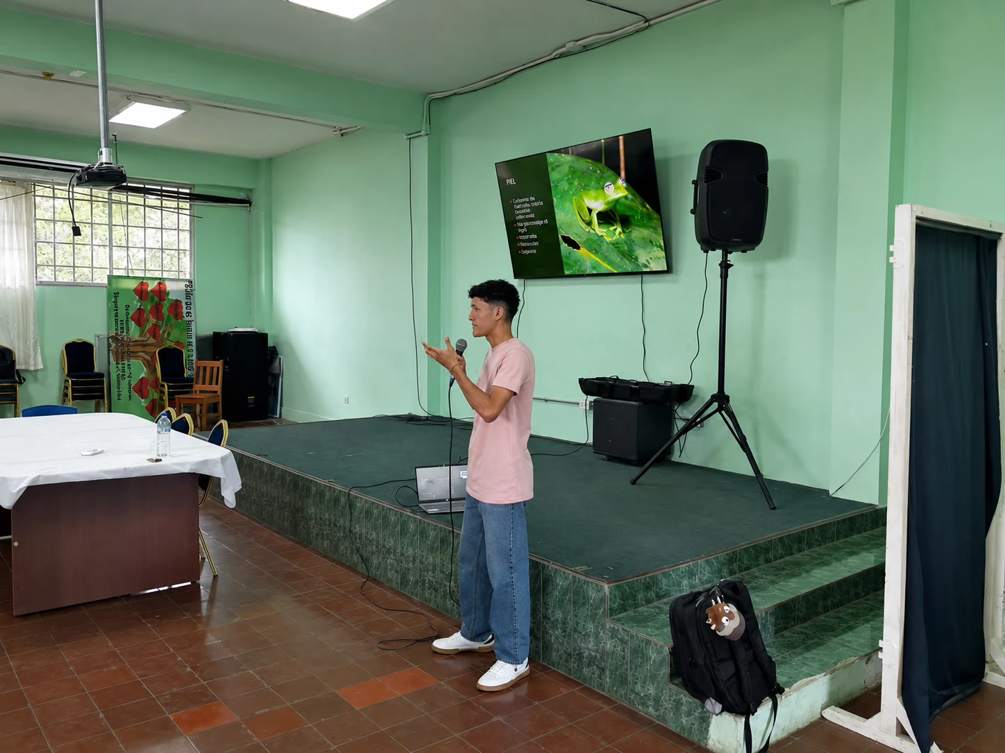 Joven de la fundación da una charla con micrófono, con una rana proyectada en pantalla